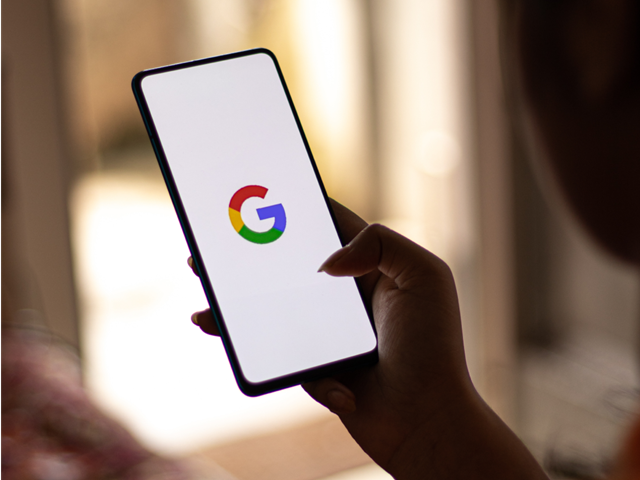 Woman holding a phone displaying Google logo on screen