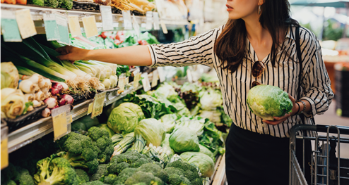 a woman choosing vegetable from a rack in a store