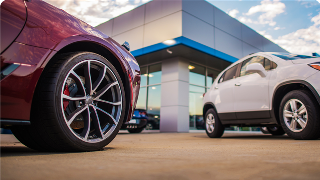 a low angle shot of 2 cars in a car yard