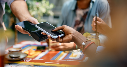 A woman holding out her phone to  pay