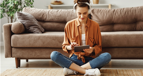 a woman sitting in front of a sofa using a tablet