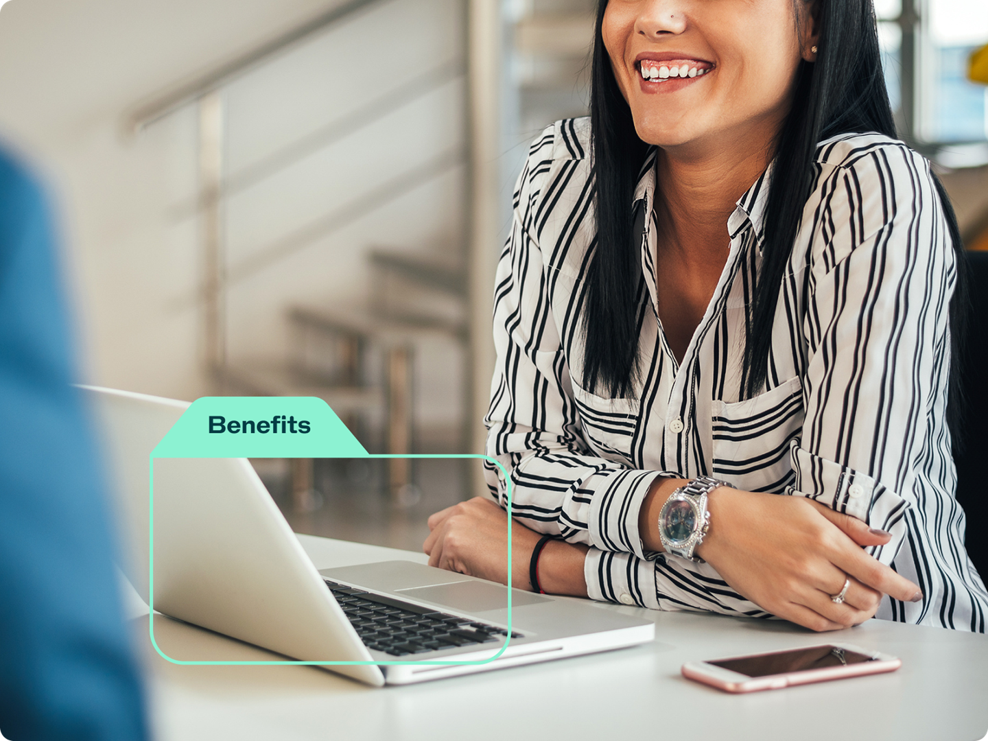 A woman sitting in front of a laptop, smiling