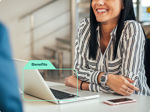 A woman sitting in front of a laptop, smiling