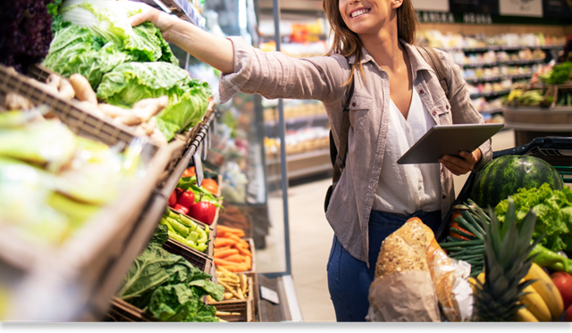 A shopper reaching for vegetables while grocery shopping. 