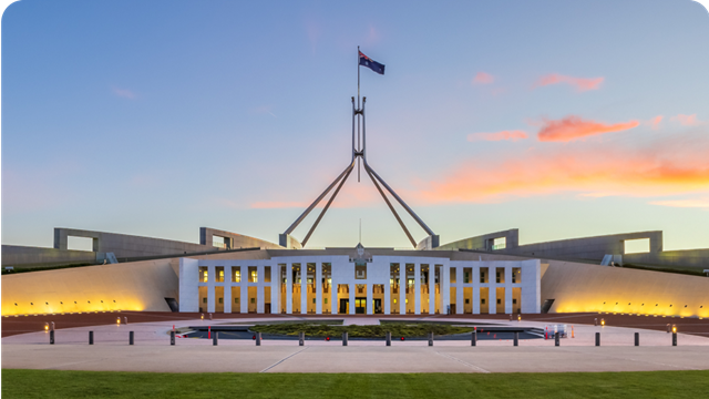 Iconic government building, Parliament House in Canberra, Australia, set against a blue sky with orange clouds.