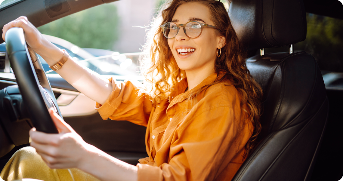 Woman with curly hair driving in sunlight.