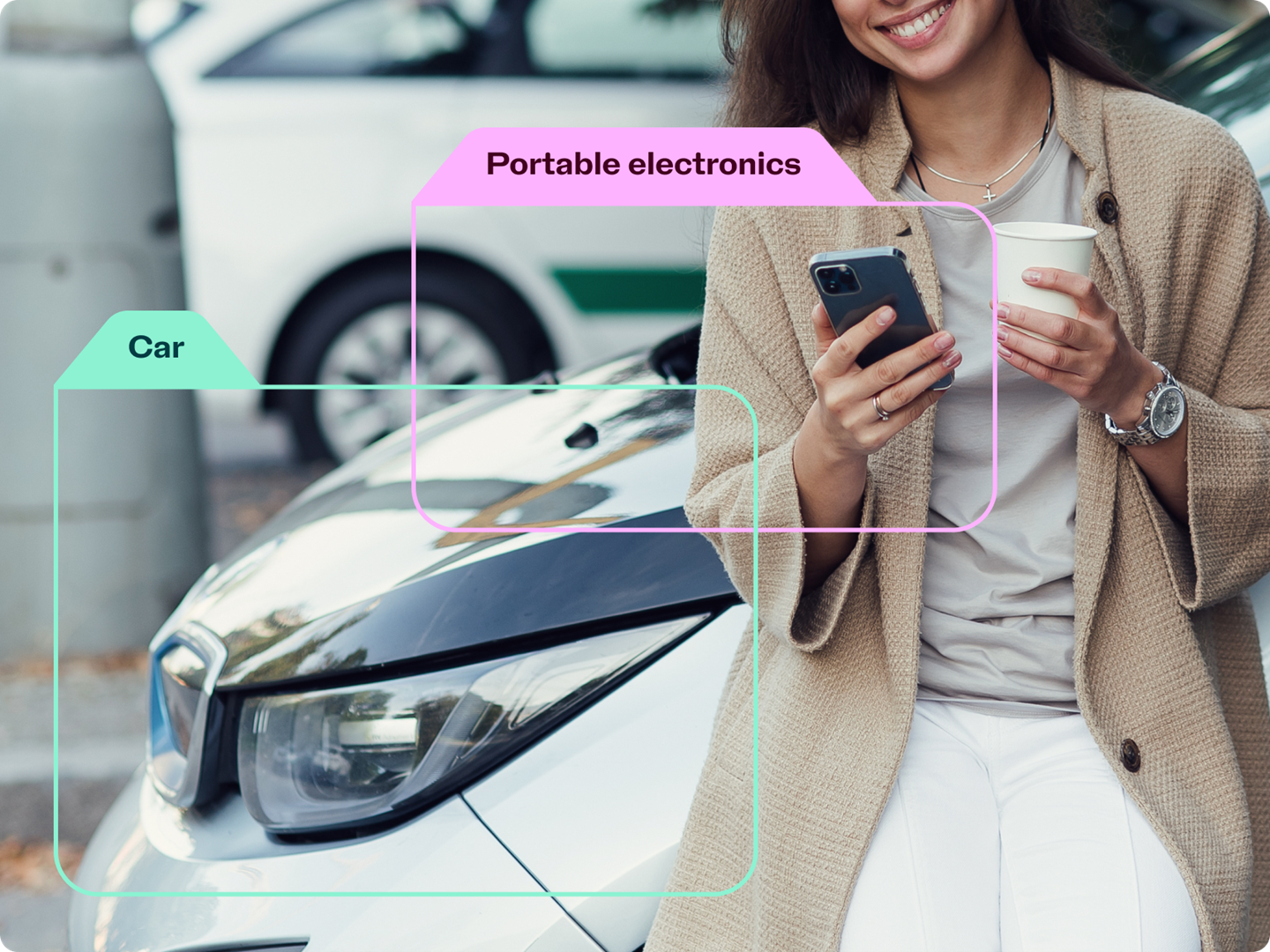 Woman holding a phone and coffee standing in front of a car